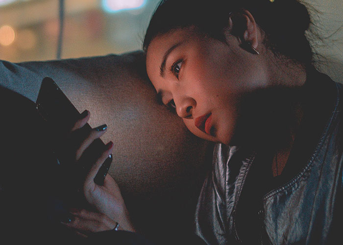 Woman looking thoughtfully at a phone screen, representing mysterious disappearances