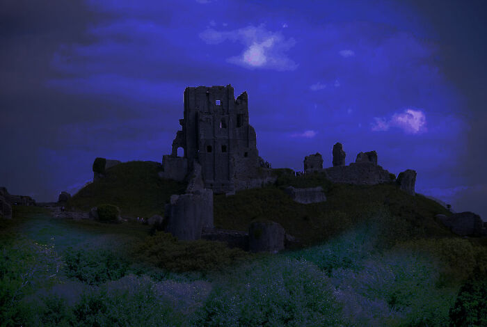 Ruined castle silhouetted against a dark blue evening sky