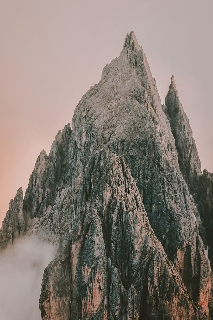 Sharp rocky mountain peaks under soft pink sky at sunset