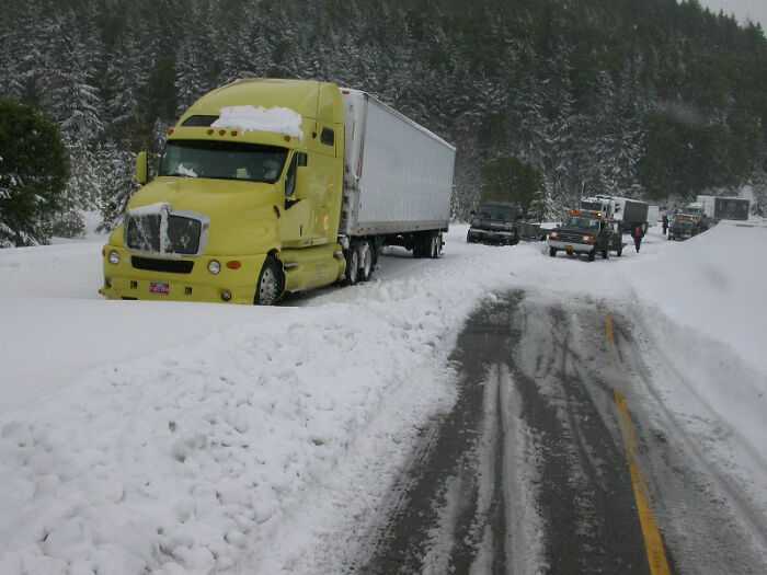 Yellow semi truck stuck in deep snow on a snowy forest road