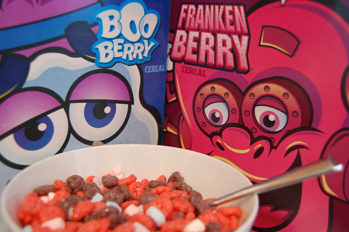 Bowl of colorful cereal pieces with Boo Berry and Franken Berry boxes in background
