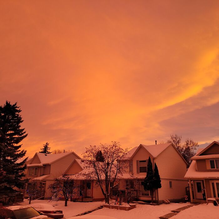 Rare sunset moment with orange glowing sky over snow-covered suburban houses
