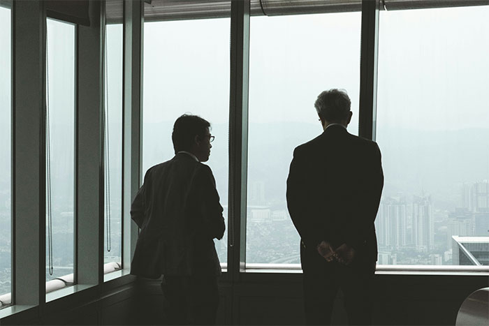 Boss discussing business while looking out office window Boss discussing business while looking out office window