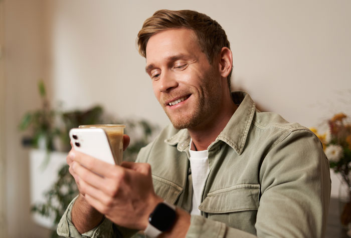 Smiling man looking at phone, possibly the unfaithful husband