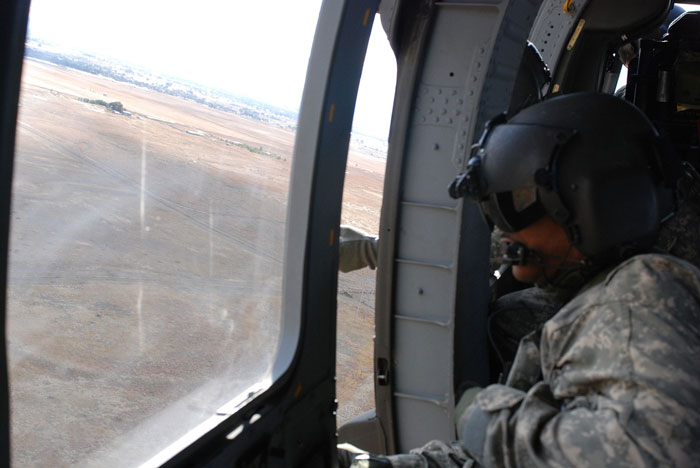 View from a helicopter window showing a soldier in military gear