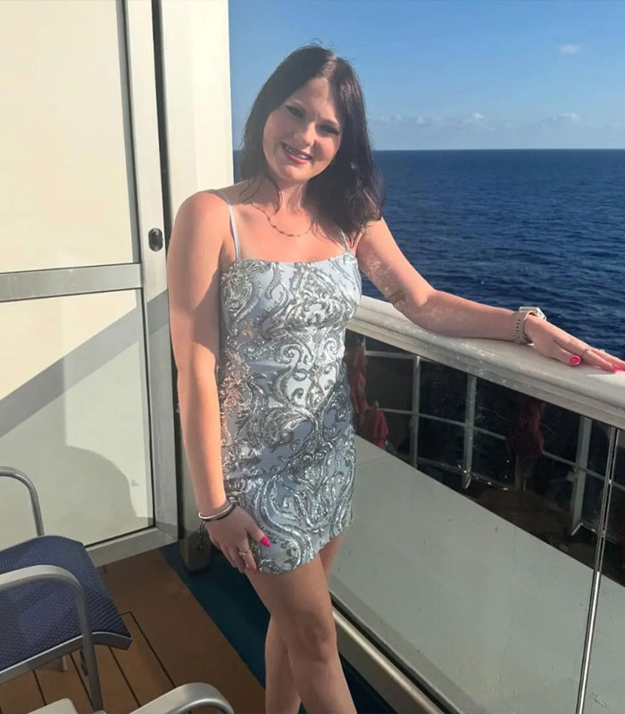 Anna Kepner posing on cruise ship balcony wearing silver dress