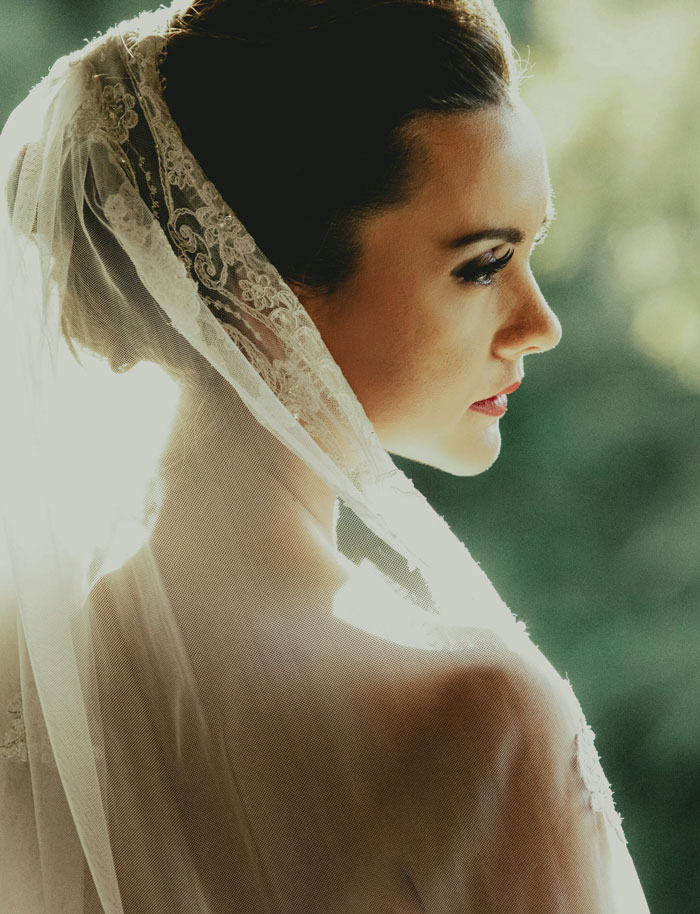 Bride with lace veil looking to side in natural light wedding photography
