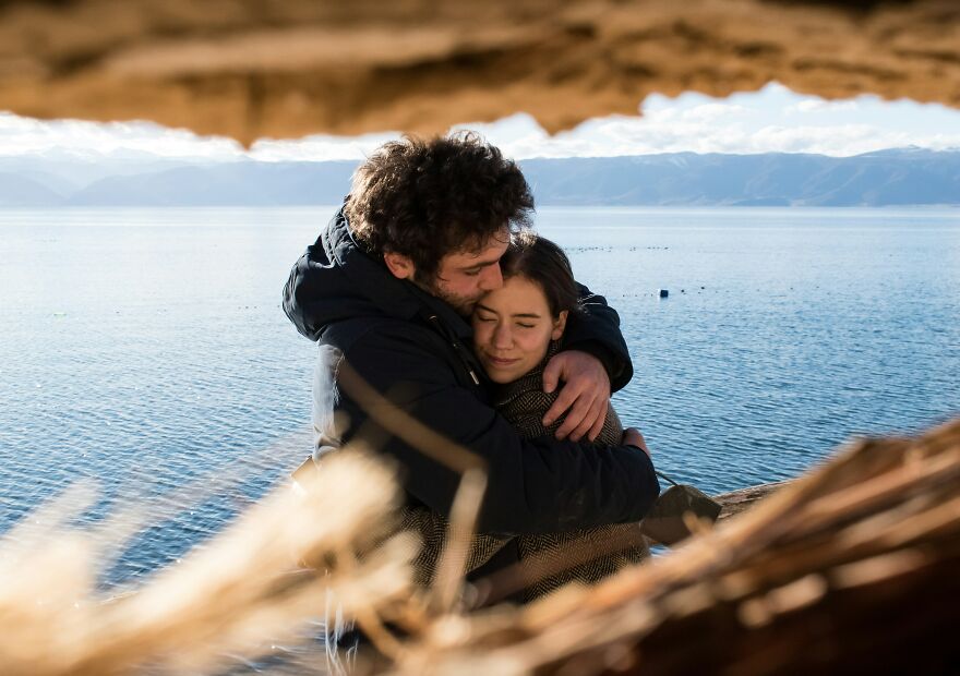 Couple embracing near water expressing happiness and emotional crying