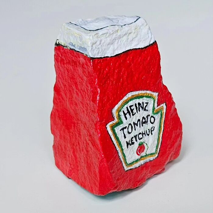 A stone creation painted as a Heinz ketchup bottle, showcasing colorful stone creations that turn rocks into iconic foods.