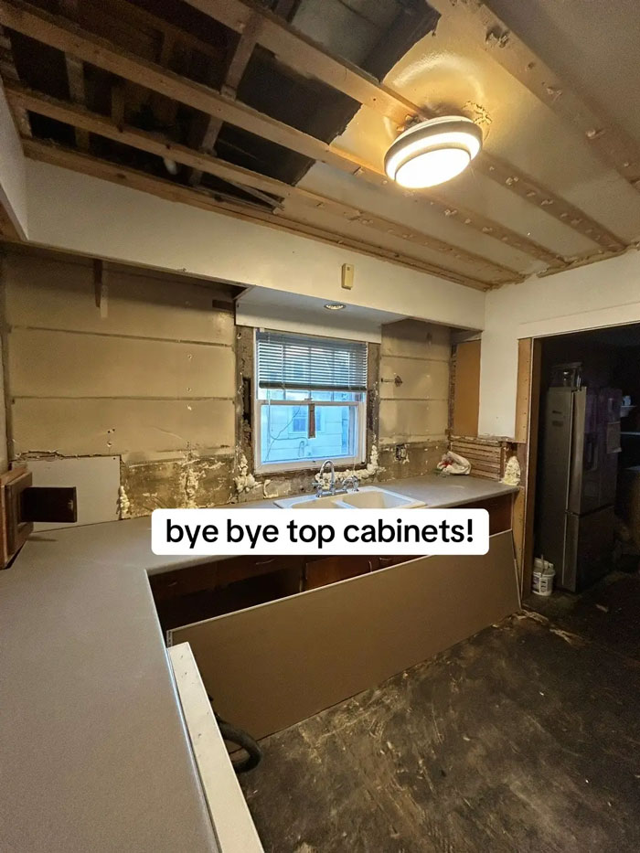 A messy kitchen during a home renovation, with walls stripped to studs and exposed ceiling joists. This expensive contractor project is not looking good.
