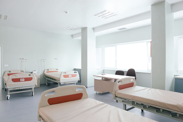 Empty psychiatric facility room with multiple hospital beds