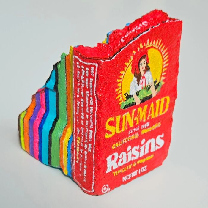 A rock transformed into a Sun-Maid Raisins box, revealing colorful layers on its side. Colorful stone creations.