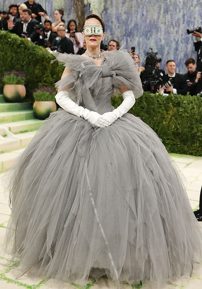 Worst dressed Met Gala 2026: A woman in a voluminous grey tulle gown with white gloves and a dollar bill over her eyes.