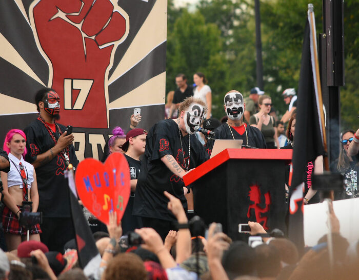 Crowd at a concert with people wearing face paint and holding signs