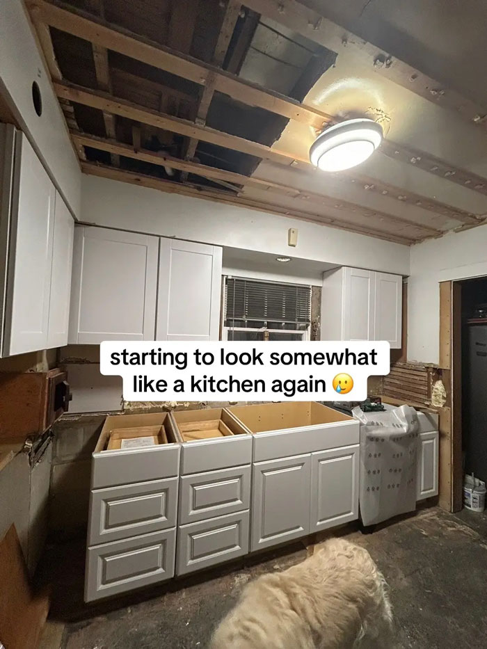Kitchen remodel aftermath with exposed ceiling, new white cabinets, and a contractor's unfinished work. Horrifying state for a home.