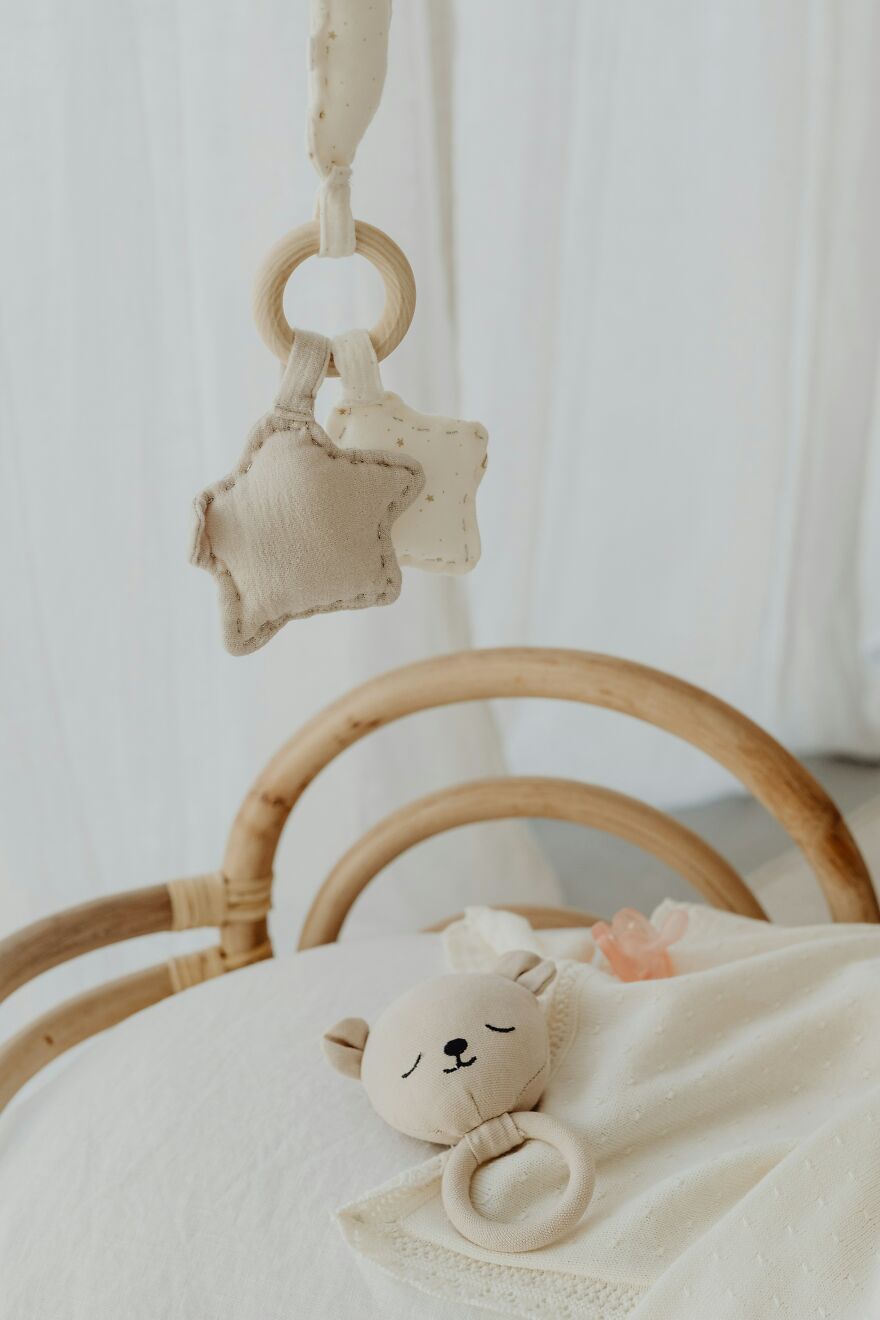 A baby's wooden crib with a teddy bear toy and a pacifier, suggesting innocence and the consequences of deception.