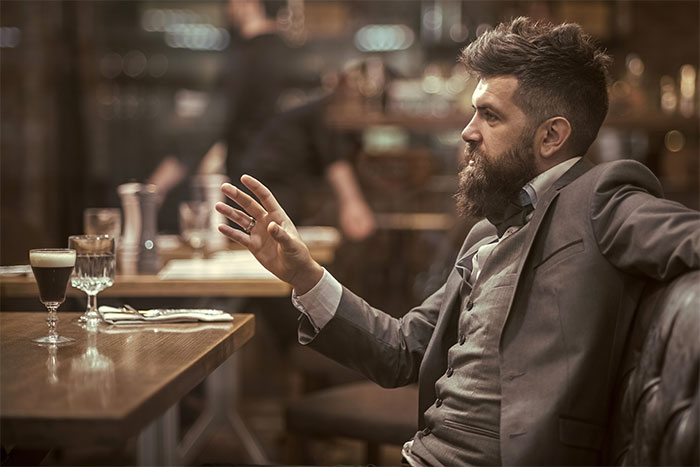 Boss sitting at dinner table looking frustrated in a restaurant setting Boss sitting at dinner table looking frustrated in a restaurant setting