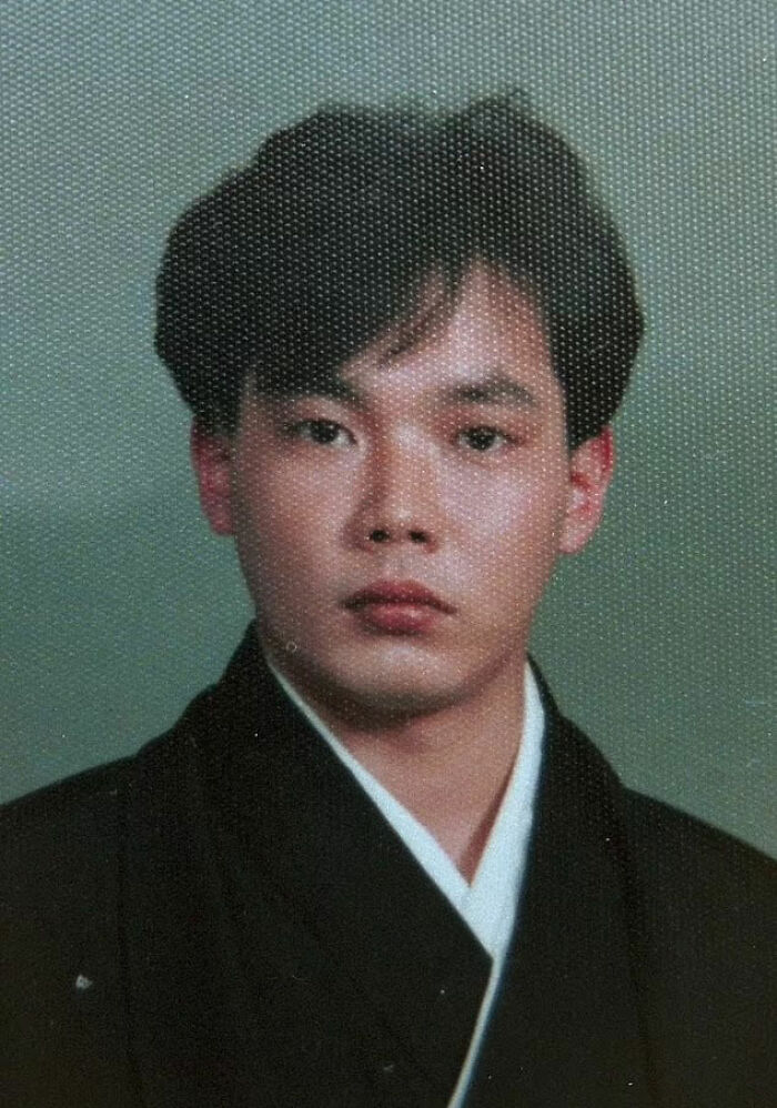 A young man with dark hair, wearing a dark kimono with a white undershirt, looking straight ahead. Disturbing d***h stories.