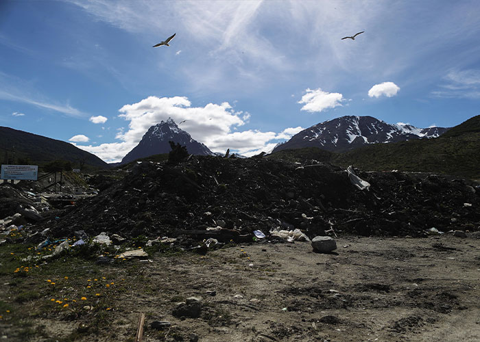 A large pile of trash and debris, with snowy mountains in the background under a blue sky. Fatal hantavirus risk.