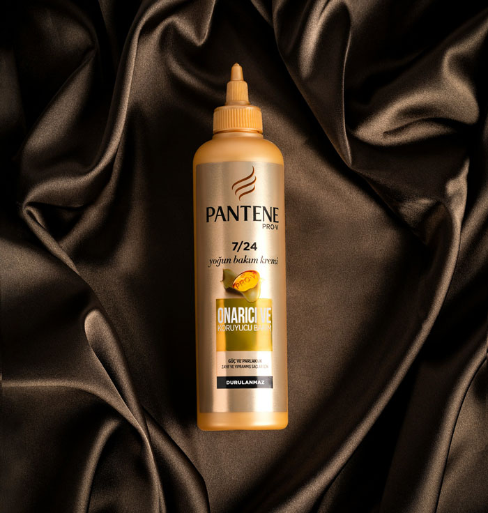 A Pantene Pro-V hair product on a dark brown silk background. Many people who grew up poor considered such items luxury.