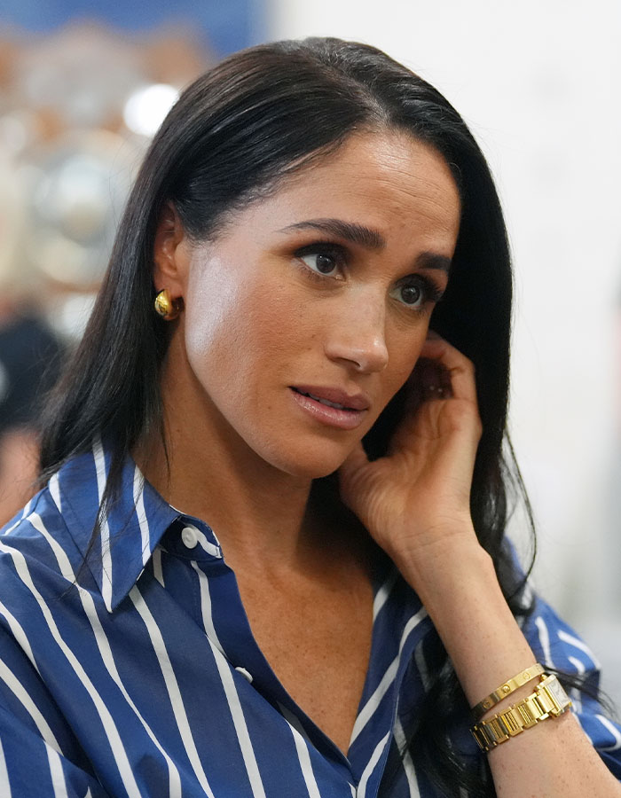 Meghan Markle, wearing a striped shirt, golden earrings and bracelet, fuels scrutiny after reports claim Sussexes are struggling. Meghan Markle, wearing a striped shirt, golden earrings and bracelet, fuels scrutiny after reports claim Sussexes are struggling.