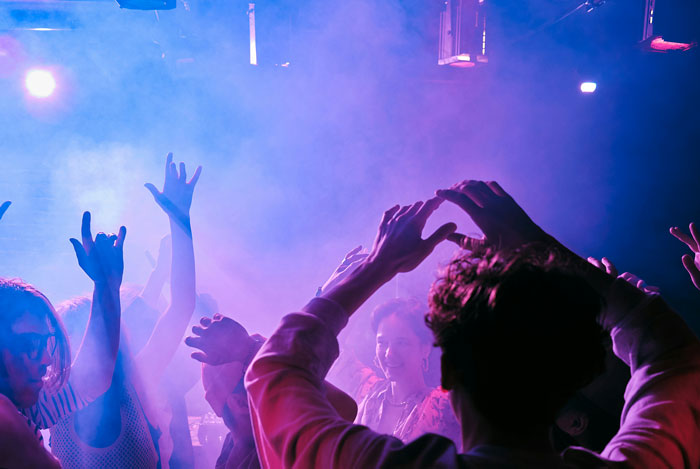 Crowd dancing with raised hands at concert with colorful lights