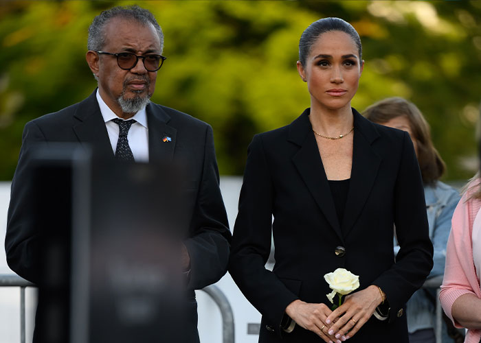 Meghan Markle standing next to WHO official holding white rose at social media safety memorial