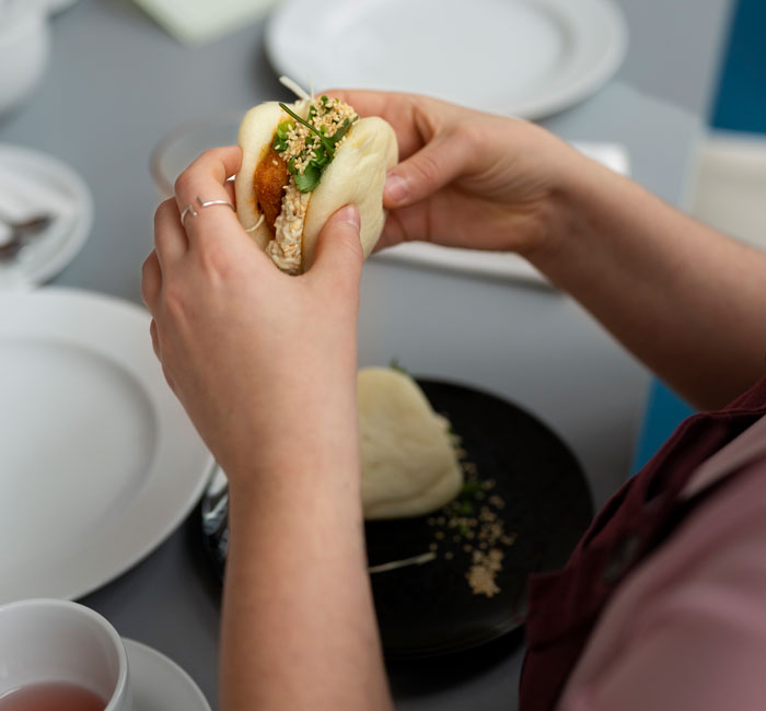 Person holding artisanal bao sandwich with fresh filling