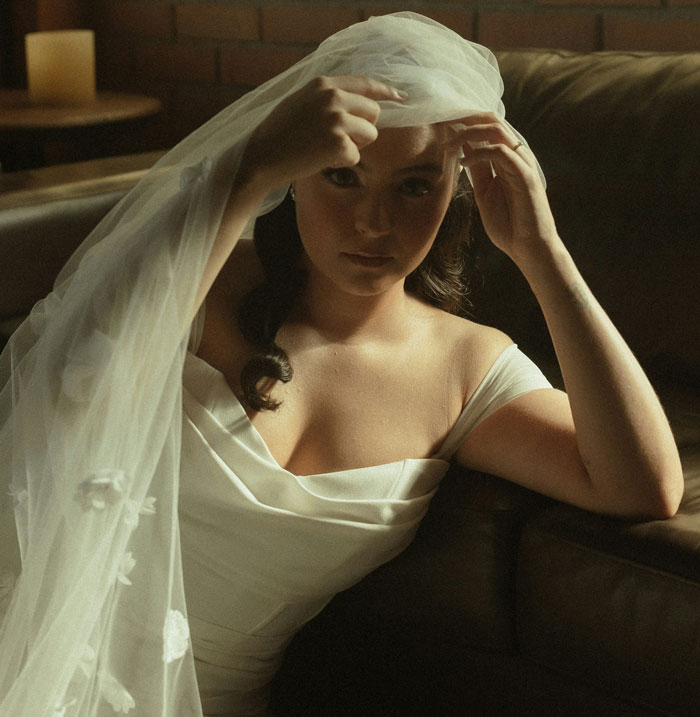 Bride with veil sitting on couch in wedding dress