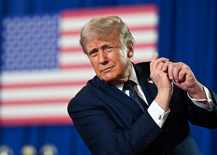 President Trump gesturing with hands in front of US flag President Trump gesturing with hands in front of US flag