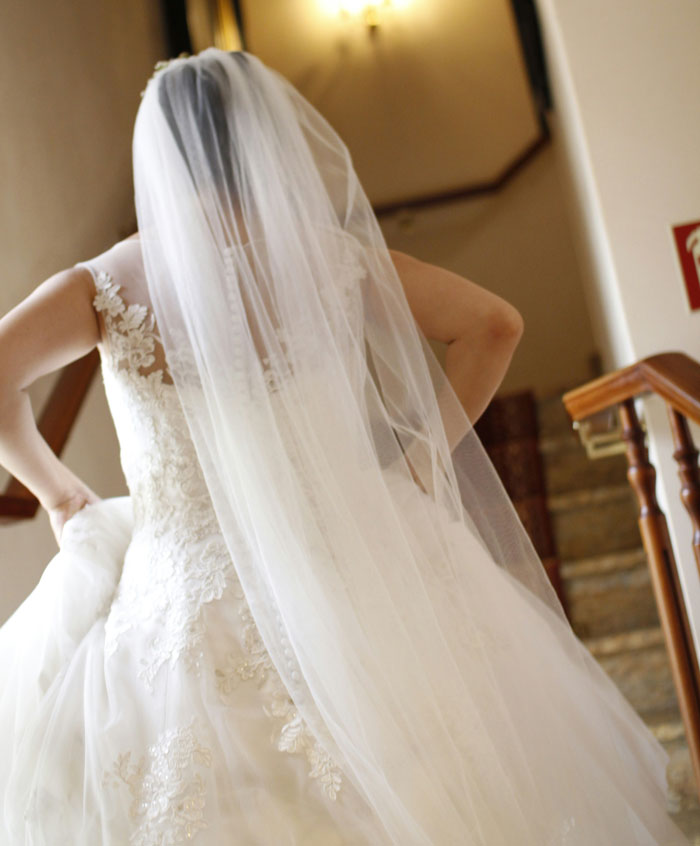 Bride wearing a lace wedding dress and long veil walking indoors