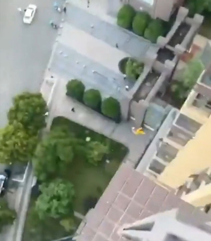 View from high window ledge overlooking street and trees below in viral falling clip