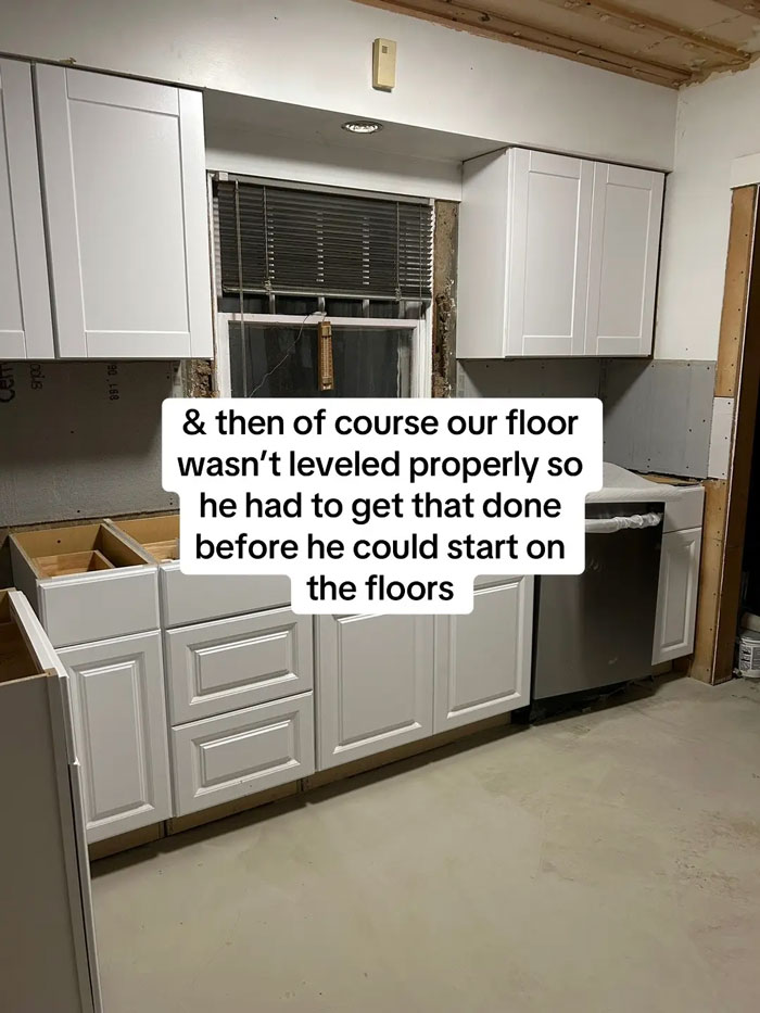 A kitchen in progress with white cabinets, a window with blinds, and exposed walls, showcasing problems with an expensive contractor.
