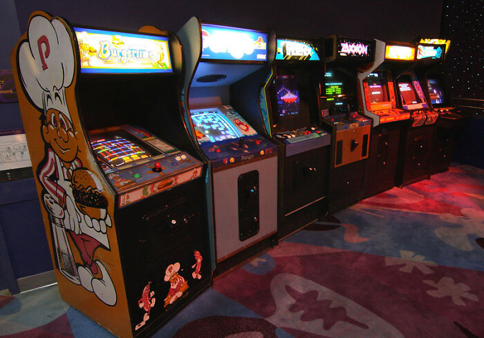 Row of vintage arcade machines in a dark room evoking backrooms nostalgia