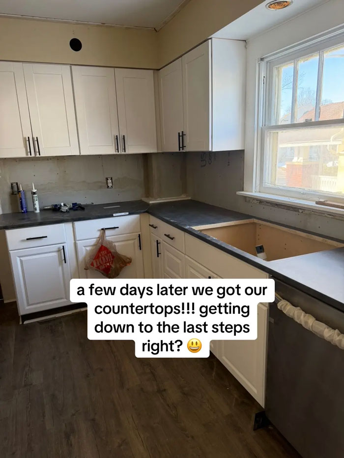 A kitchen in progress, white cabinets installed, dark countertops partially in place, highlighting expensive contractor work issues.