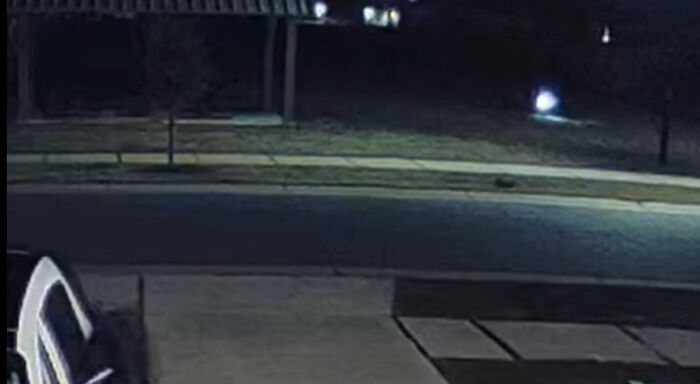 Night vision surveillance image showing a dark street with a bright, blurry spot. Is it a creature from the viral video? Night vision surveillance image showing a dark street with a bright, blurry spot. Is it a creature from the viral video?