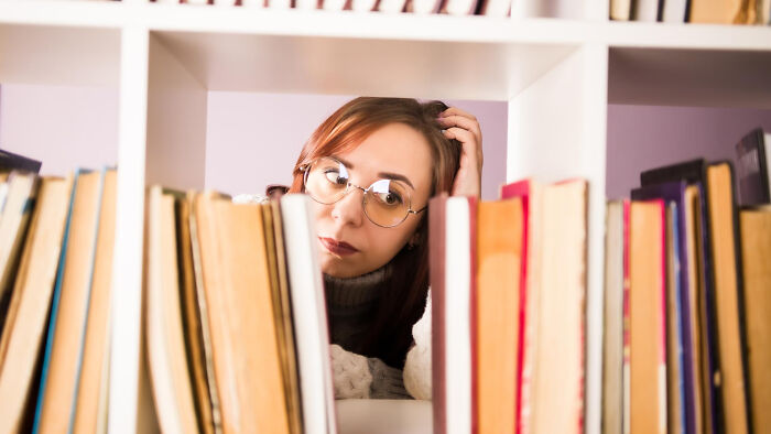 Person with glasses looking through bookshelves showing January 6 confusion