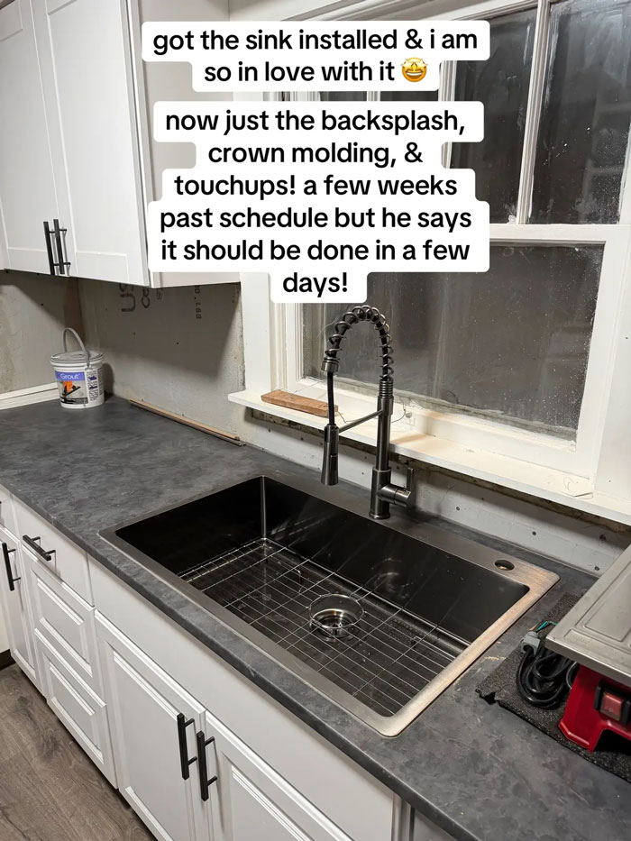 A newly installed sink with a black faucet in a kitchen under construction, showing work from an expensive contractor.