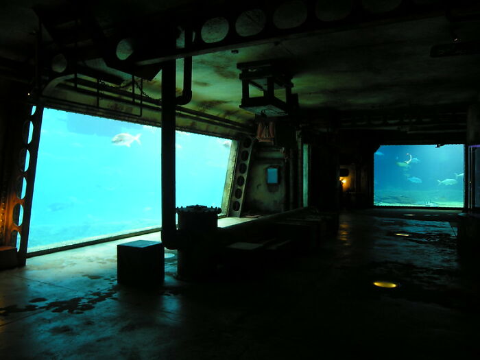 Dark underwater level with fish viewed through large windows in backrooms style