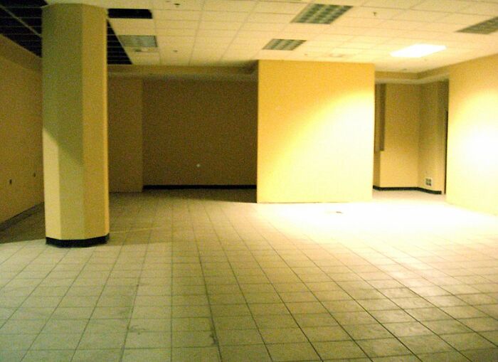 Empty tiled room with yellow walls evoking the Backrooms environment