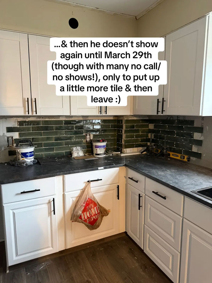 A kitchen with partially installed dark green subway tile backsplash and white cabinets, reflecting a bad contractor experience.