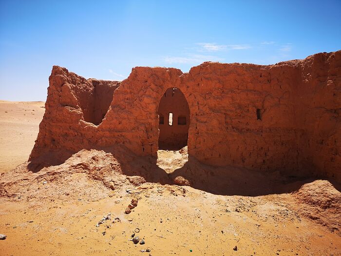 Ruined mud brick building in a desert setting under clear sky