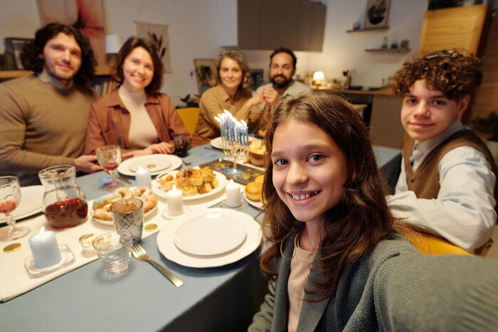 Family celebrating at dinner table with birthday cake and candles