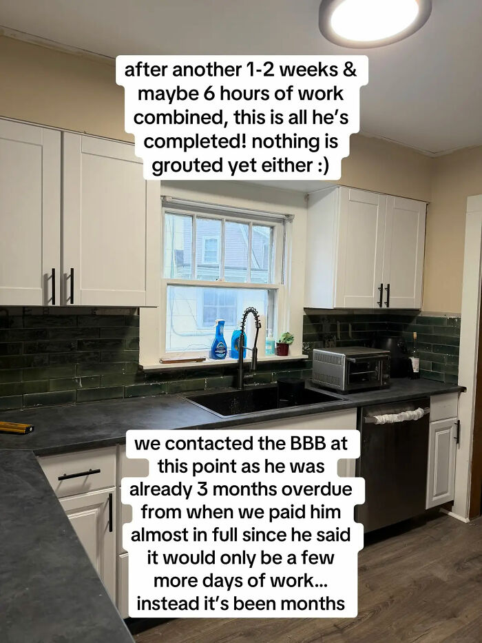 A partially renovated kitchen with white cabinets and dark green subway tile. The expensive contractor left it unfinished.