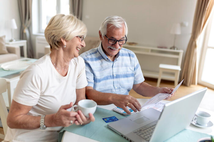 Senior couple reviewing bills and using laptop reflecting conspiracy theory moments explained by facts
