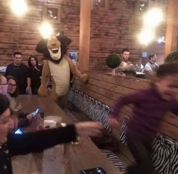 People reacting with a character in a lion costume in a rustic restaurant