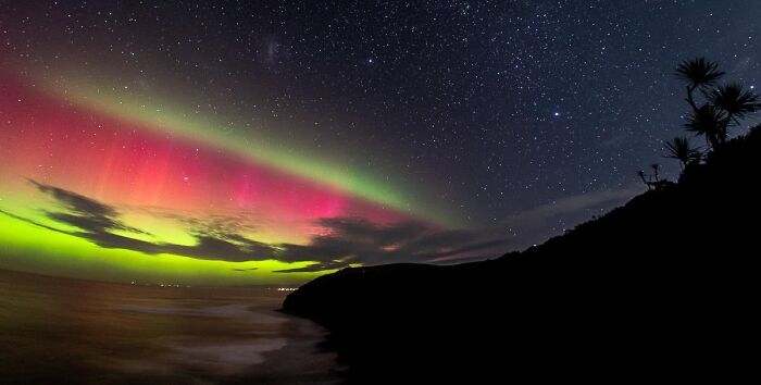 Rare rare moment of aurora borealis with vibrant red and green lights under starry sky
