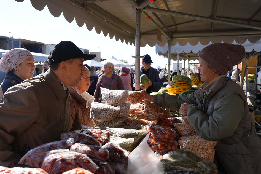 Customers at an outdoor market, with a vendor selling nuts and dried goods, reflecting on countries with the worst diets.