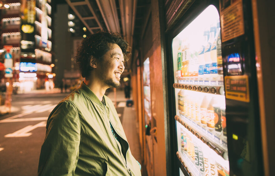 A smiling man looks at a Japanese vending machine at night, highlighting these Japanese things.