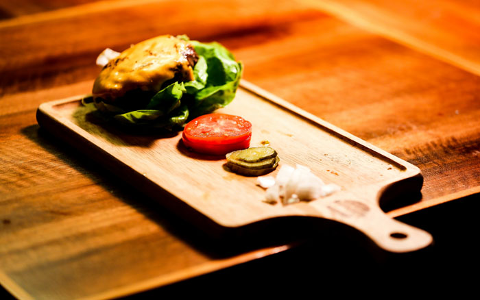Close-up of artisanal cheeseburger with lettuce and tomato on wooden board